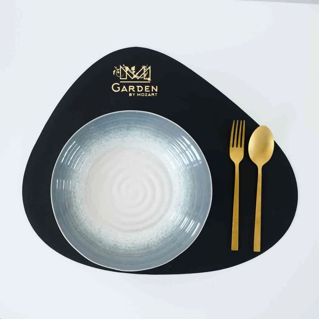 Elegant black faux leather teardrop placemat on a modern dining table with white dinnerware