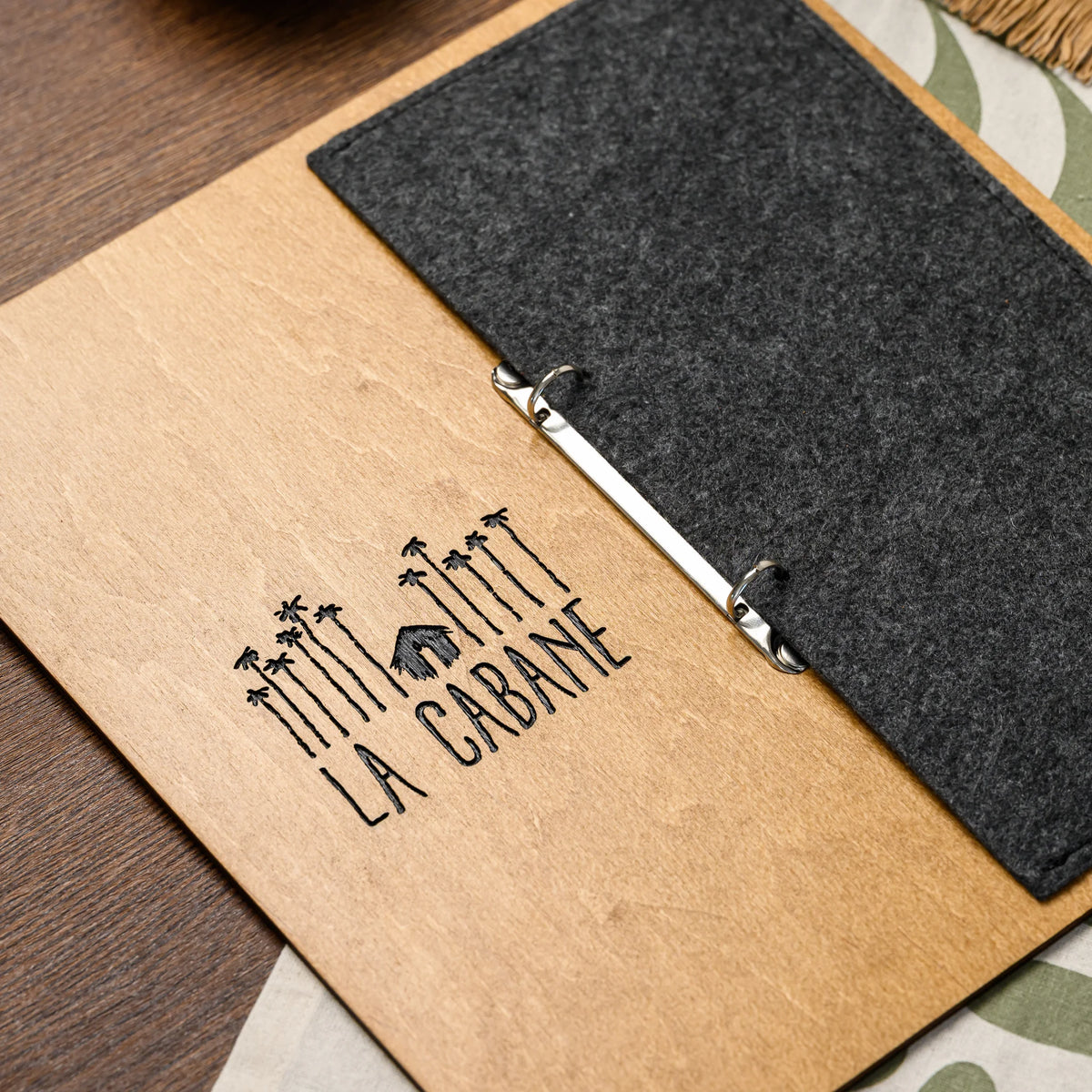 A macro view of an engraved logo on the plywood front of the menu board beside the felt cover, angled 