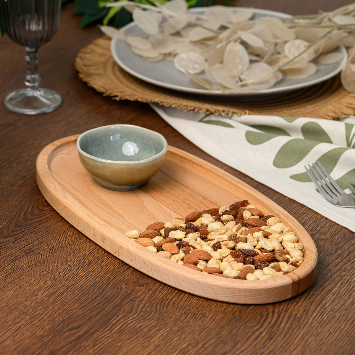 Overhead view of the beech wood oval serving board with a ceramic bowl and nuts scattered at one end