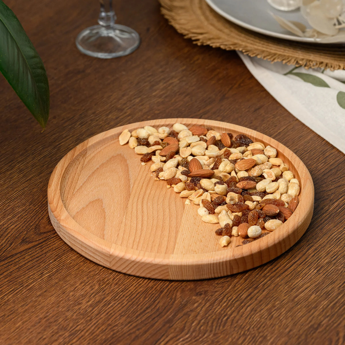 Overhead view of the round beech wood plate with mixed nuts and raisins covering half of its surface