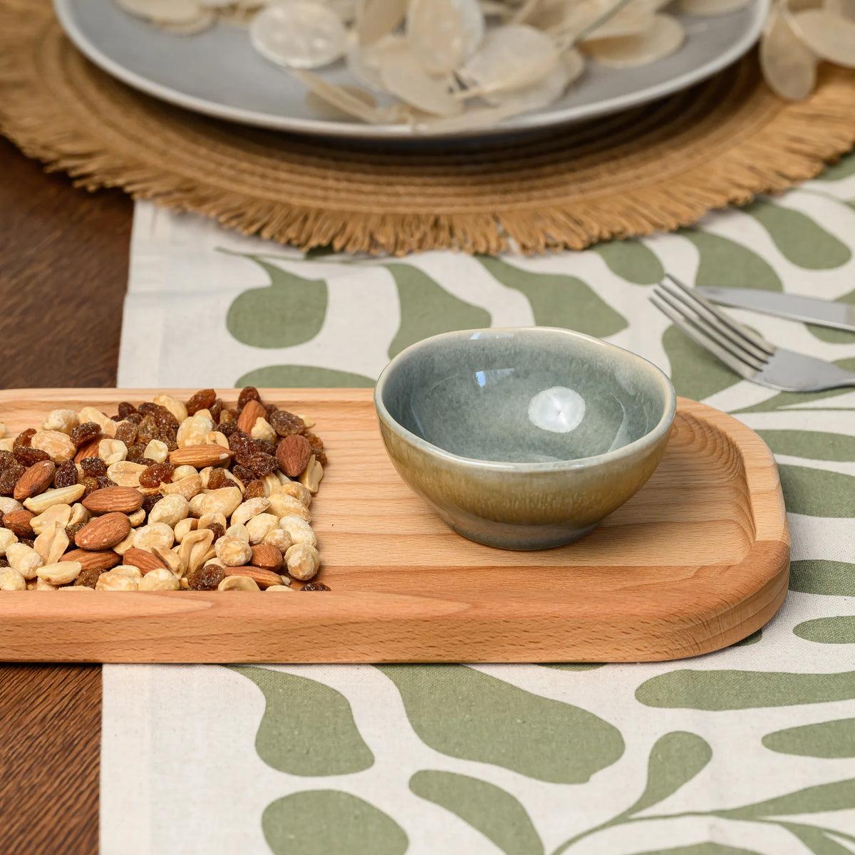 Ceramic bowl and a small pile of mixed nuts placed at opposite ends of the beech wood rectangular board