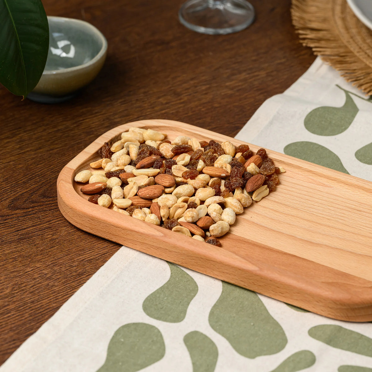 Close-up of mixed nuts and raisins filling the corner of the beech wood rectangular serving board, grain visible