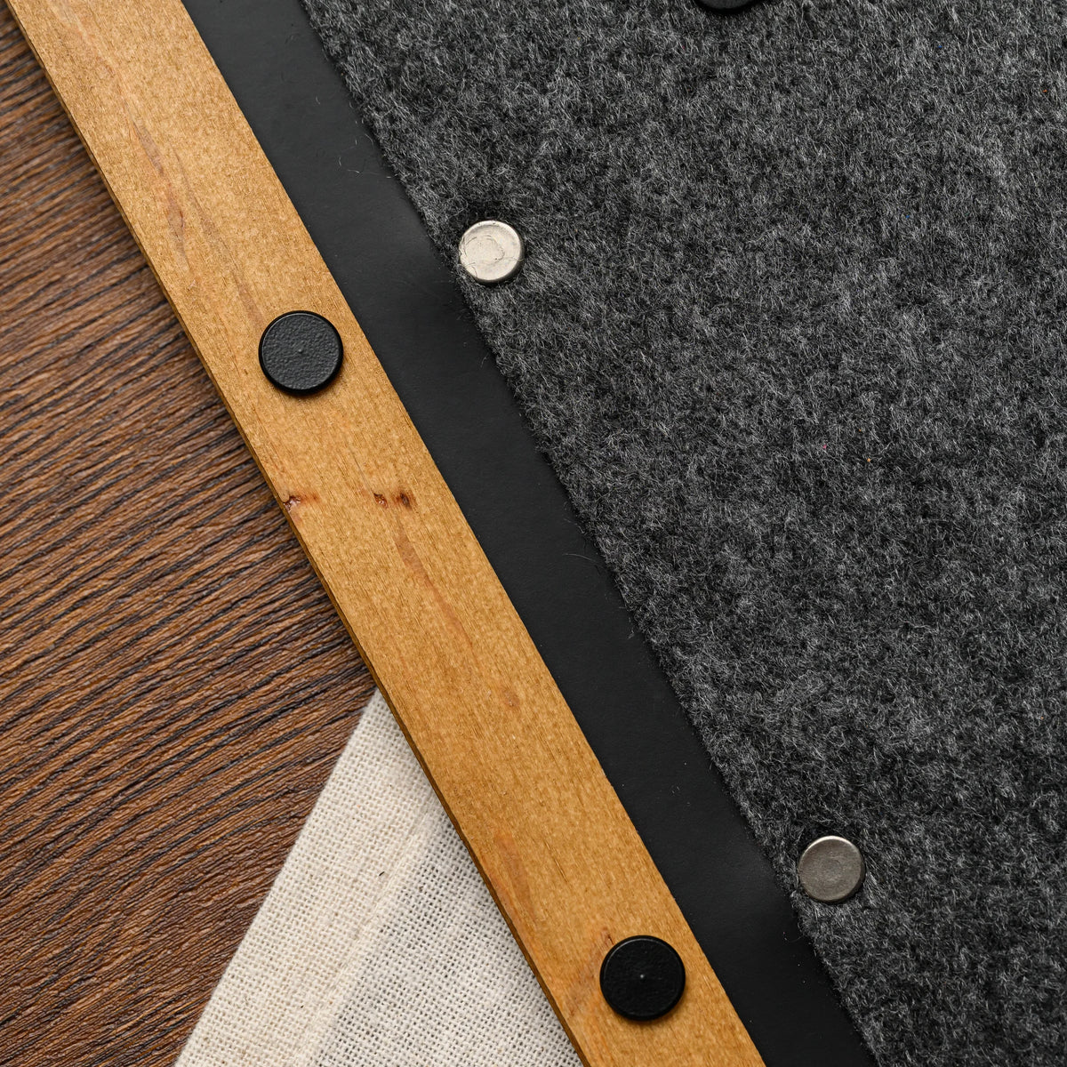 A macro view of a stitched felt cover corner and wood spine edge on the menu folder, near a linen napkin