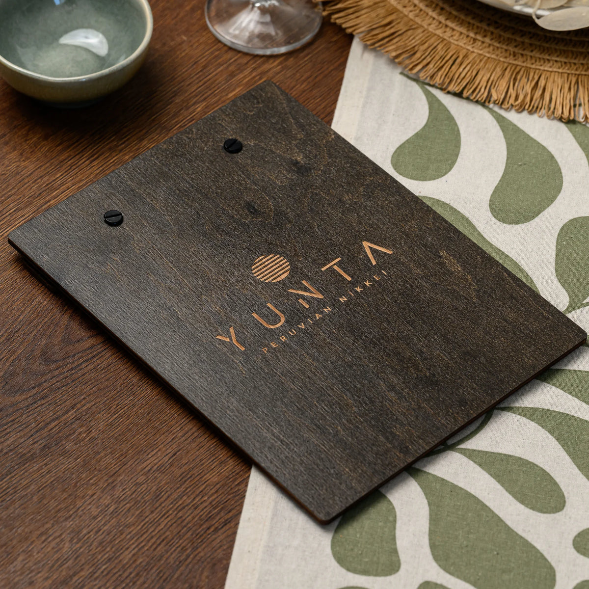 A macro view of an engraved logo detail on the dark plywood back panel of this felt-front menu board 